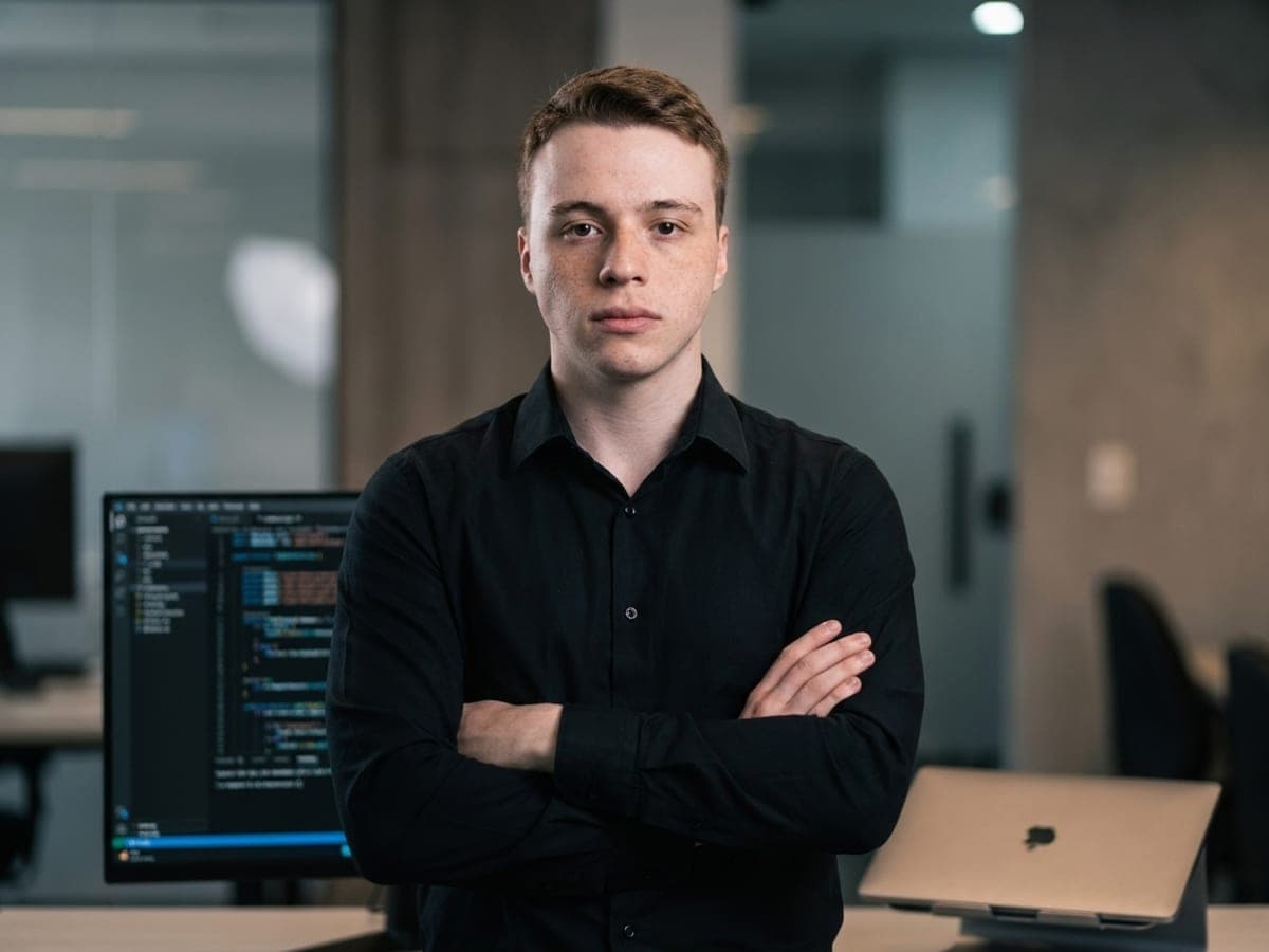 Leonardo Macedo, co-fundador da DeepCodeStudio, de braços cruzados no escritório